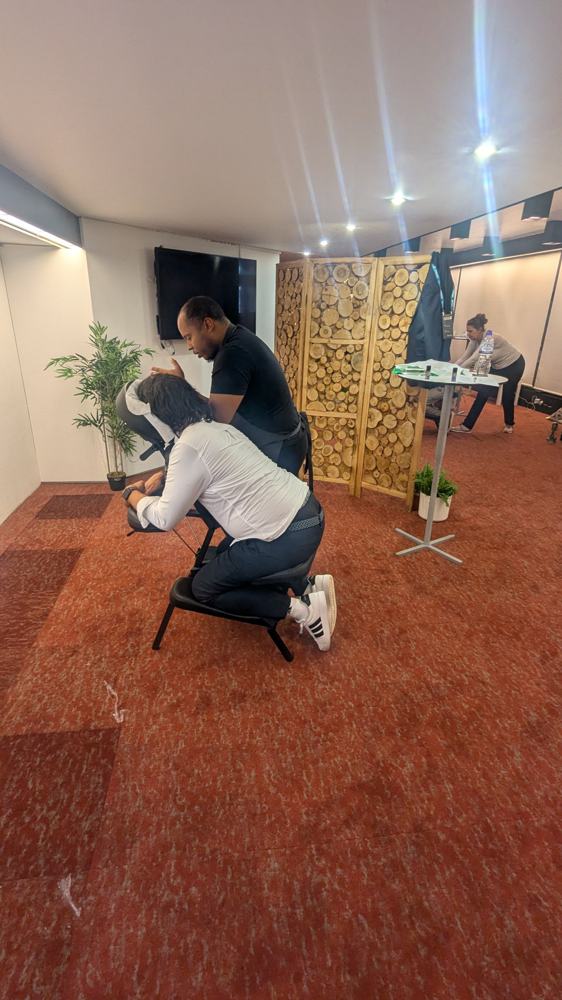 Therapist working on an employee's shoulders during a fully-clothed chair massage