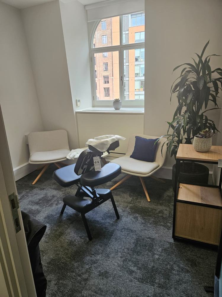 Quiet office room set up for on-site chair massage with plants and soft seating